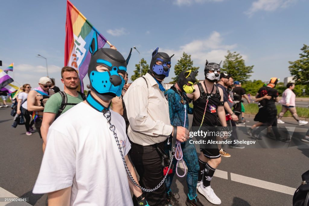 a group of people dressed as pups wearing collars and leashes and walking in a pride parade