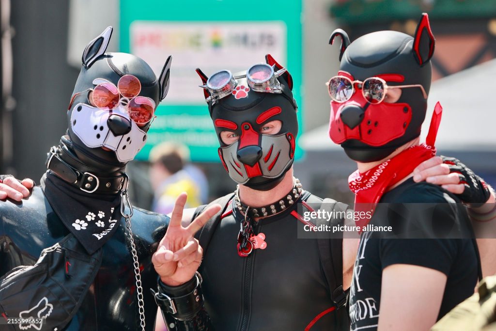 three people dressed up as puppies standing together with red and black clothing and puppy masks